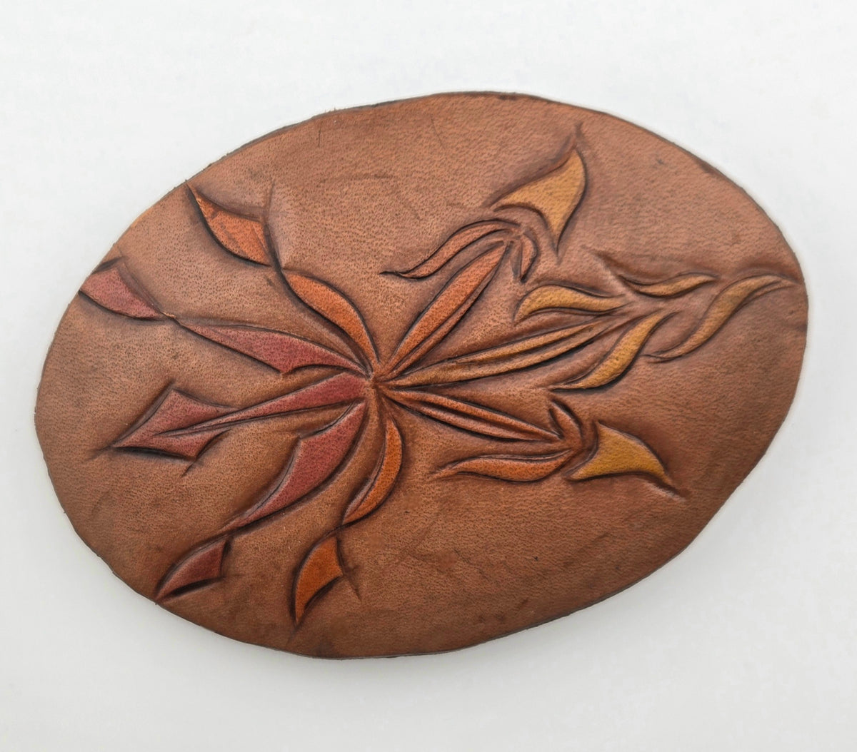 Front of the Hand Tooled Leather Vintage Belt Buckle — Oval Rust & Gold Pinwheel, showing an oval face with a two-tone rust and gold pinwheel star flower.