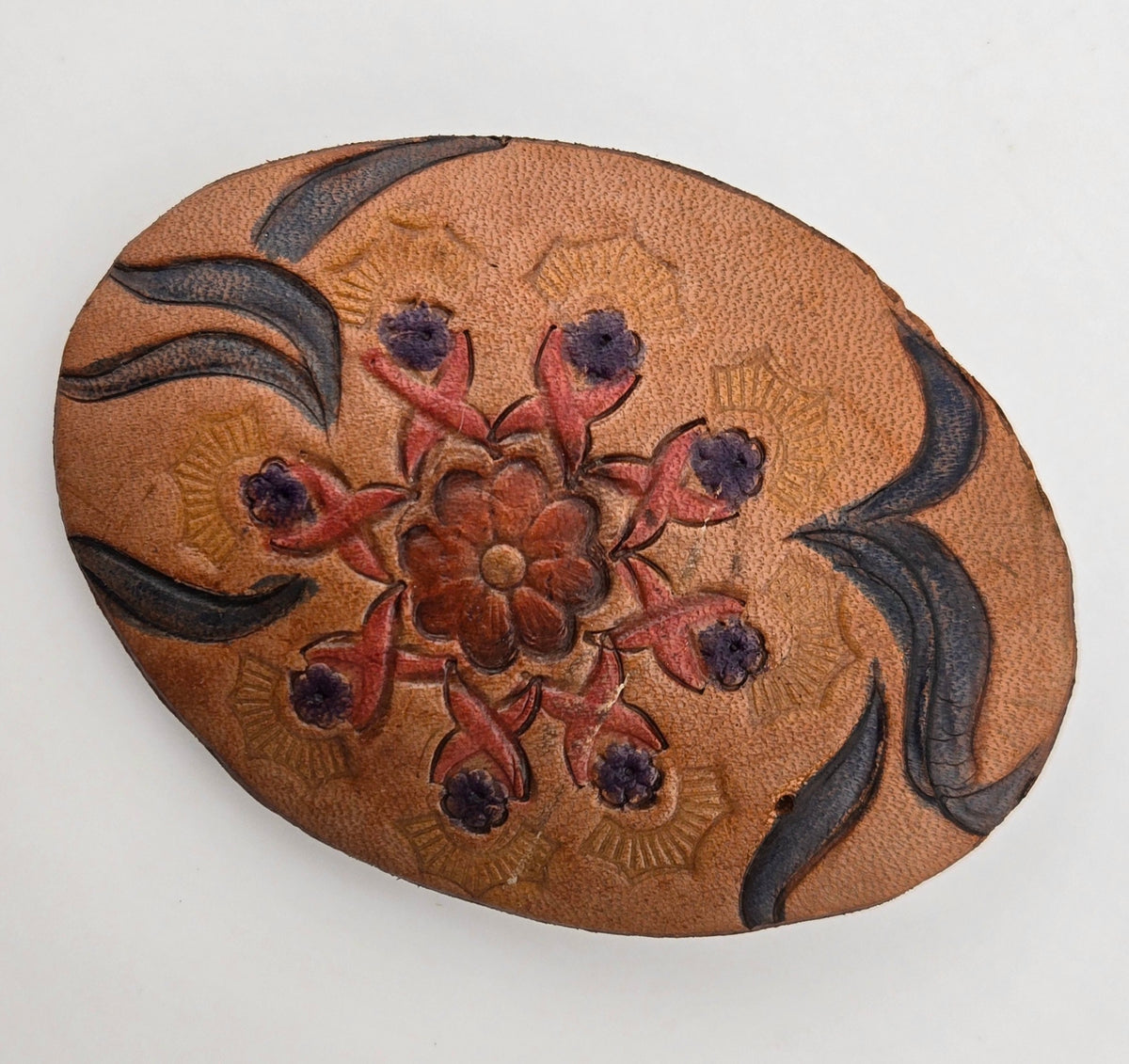 Front of the Hand Tooled Leather Vintage Belt Buckle — Oval Red Star Flower, showing an oval face with a red star flower dotted in purple, framed by navy scrolls.