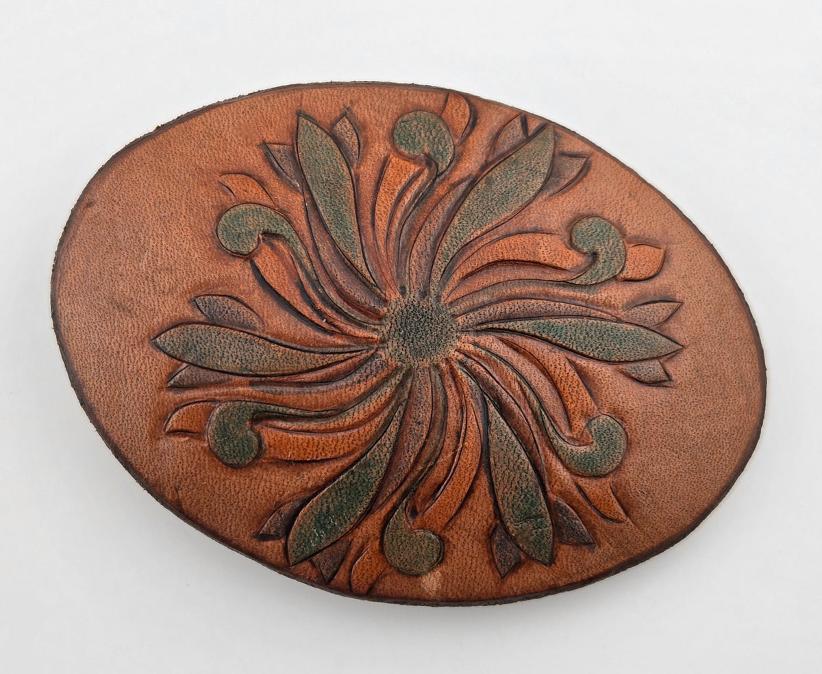 Front of the Hand Tooled Leather Vintage Belt Buckle — Oval Green Pinwheel Bloom, showing an oval face with a green-tinted pinwheel bloom radiating across tan leather.