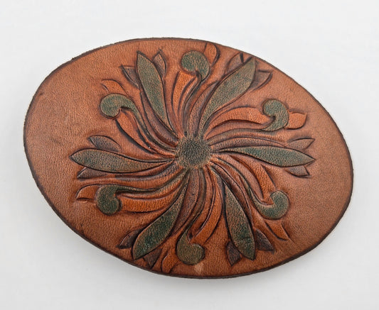 Front of the Hand Tooled Leather Vintage Belt Buckle — Oval Green Pinwheel Bloom, showing an oval face with a green-tinted pinwheel bloom radiating across tan leather.