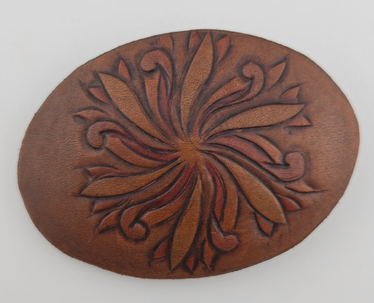 Front of the Hand Tooled Leather Vintage Belt Buckle — Oval Pinwheel Flower, showing an oval face with a swirling pinwheel flower in tan and rust on dark brown leather.