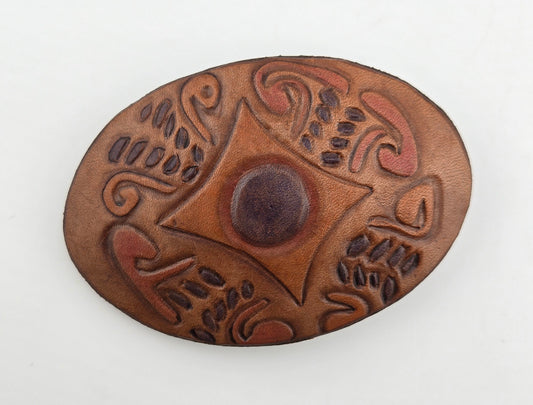 Front of the Hand Tooled Leather Vintage Belt Buckle — Oval Center Medallion Star, showing an oval face with a dark center medallion set in a carved star and scroll pattern.