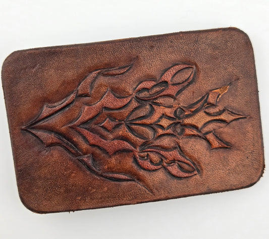 Front of the Hand Tooled Leather Vintage Belt Buckle — Interlocking Carved Leaves, showing bold interlocking carved leaves in relief across a dark brown face.