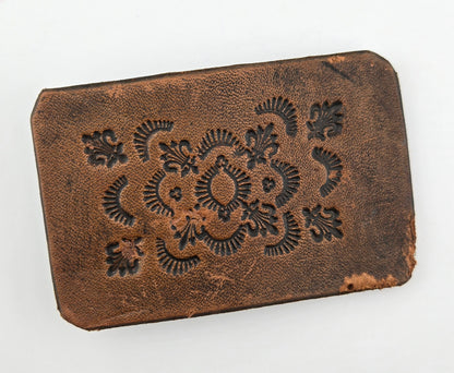 Front of the Hand Tooled Leather Vintage Belt Buckle — Fleur-de-Lis & Sunburst, showing fleur-de-lis stamps ringed by radiating sunburst arcs in dark tooling on a tan-brown face.