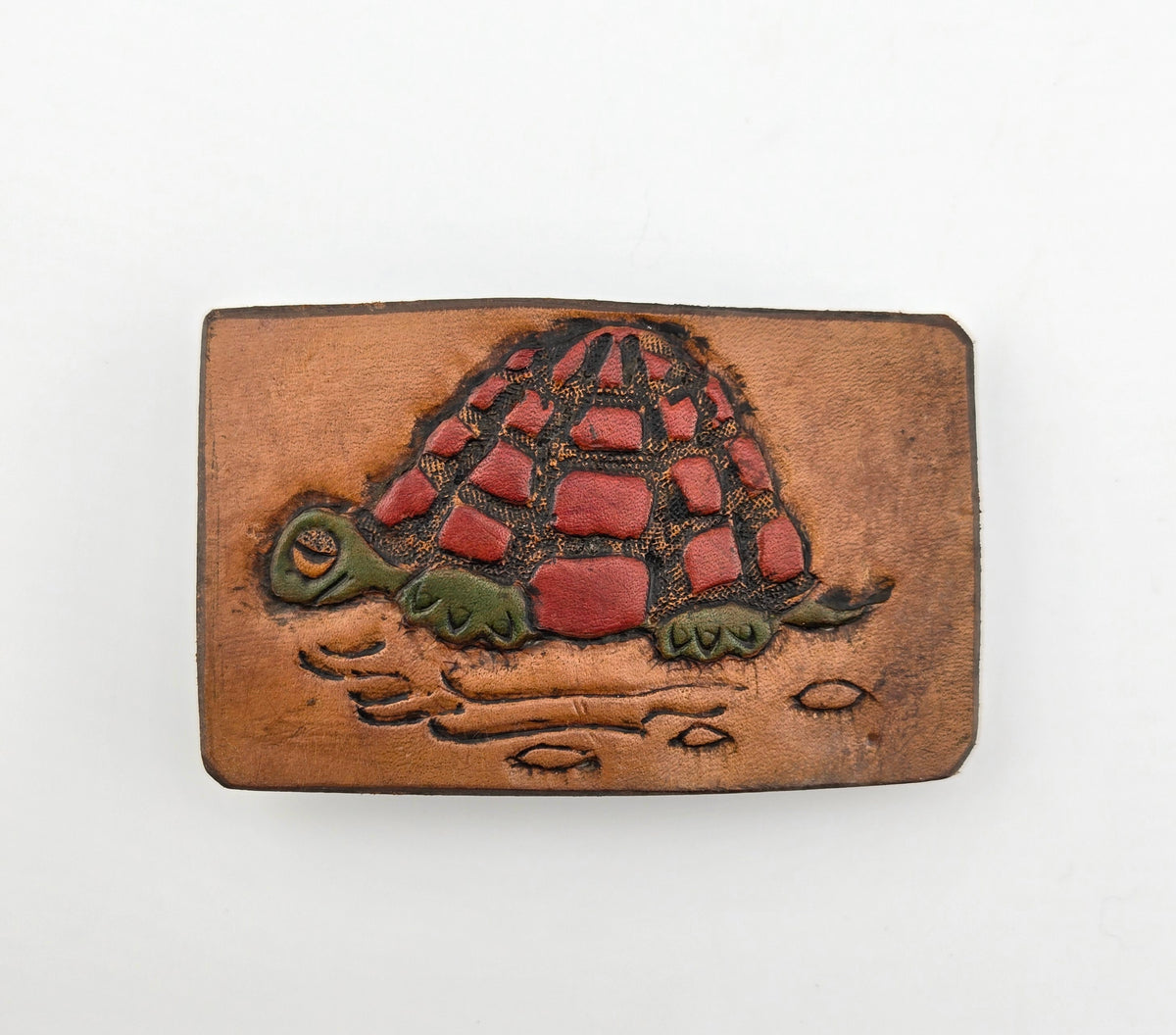 Front of the Hand Tooled Leather Vintage Belt Buckle — Turtle with Red Patchwork Shell, showing a turtle with a bold red patchwork shell and green head and legs on a tan leather face.